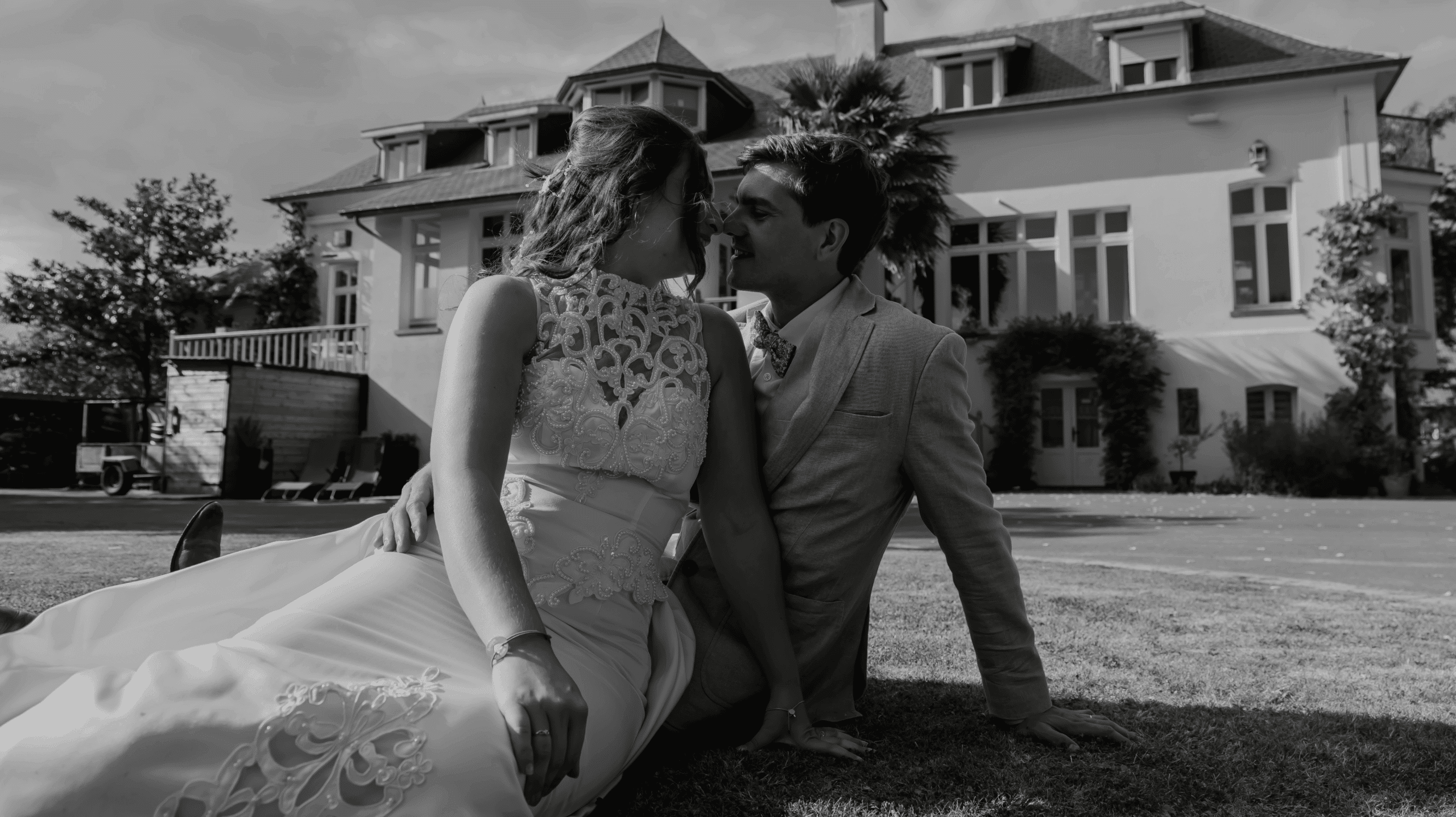 Couple de mariés assis dans l'herbe devant le Manoir Fleuri, lieu de mariage à Groffliers sur la Côte d'Opale