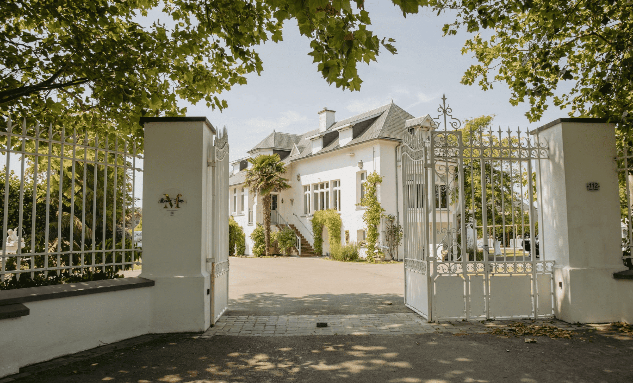 Le portail ouvert du Manoir Fleuri et sa façade blanche, lieu de réception privatisable pour une soirée Halloween sur la Côte d'Opale